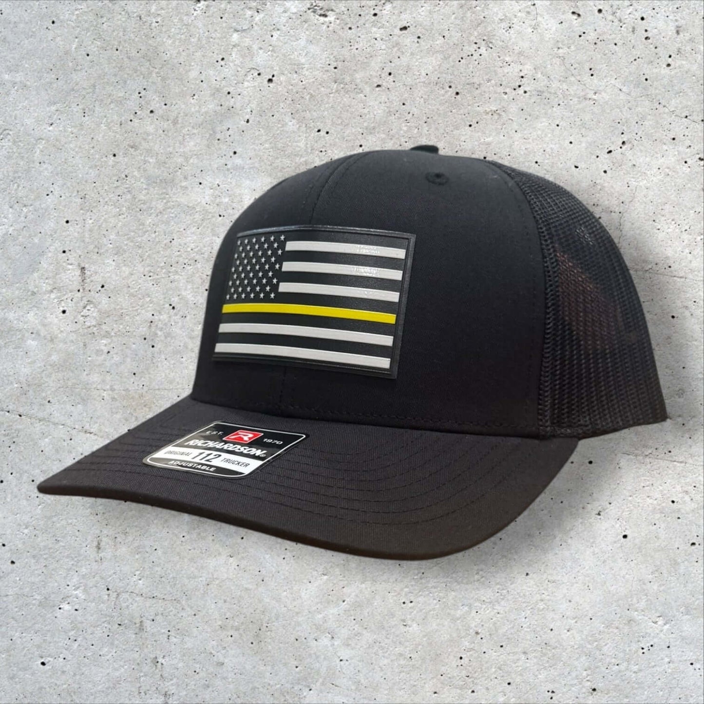 Thin Yellow Line Hat featuring a UV-printed American flag patch, durable black Richardson 112 trucker design.